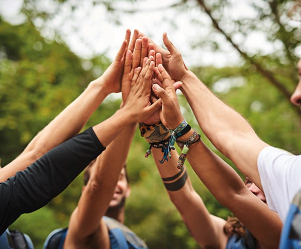 een team dat ealkaar een high five geeft in de natuur