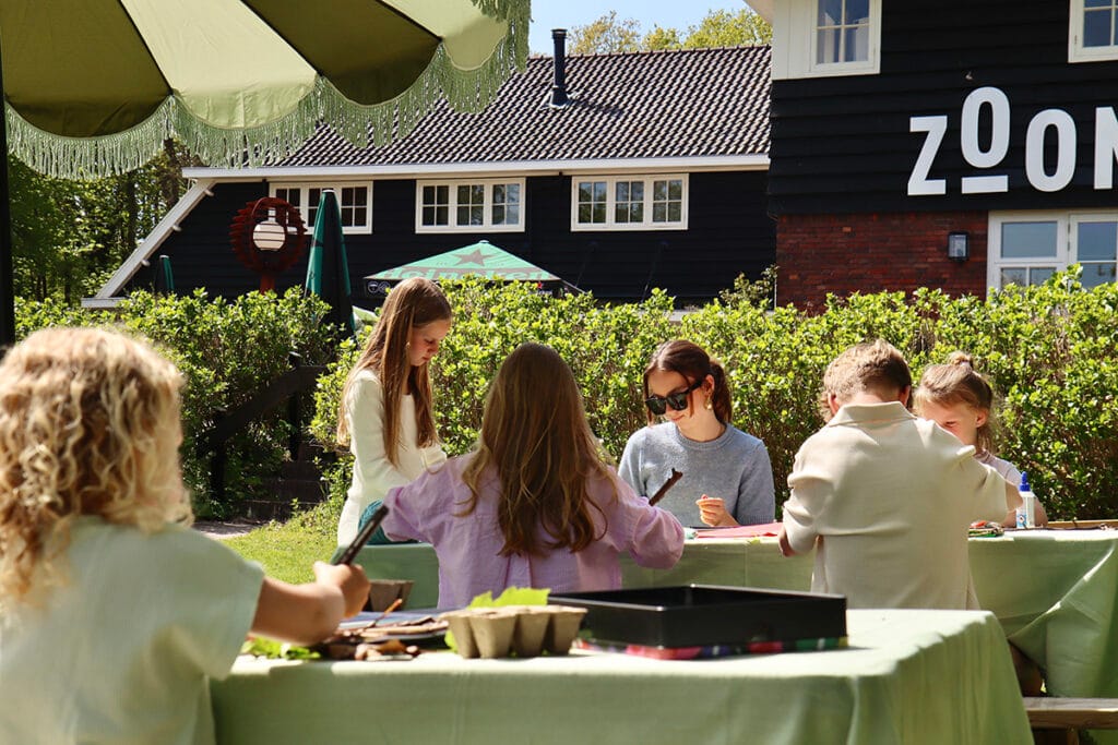 Kinderen zijn buiten aan het knutselen aan een picknicktafel.
