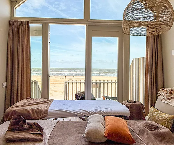 Strandhuisje met massagetafels erin en uitzicht op het strand en de zee.
