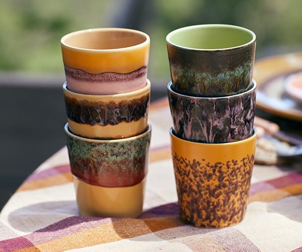 Kopjes van het merk HKLIVING staan opgestapeld op een tafel.